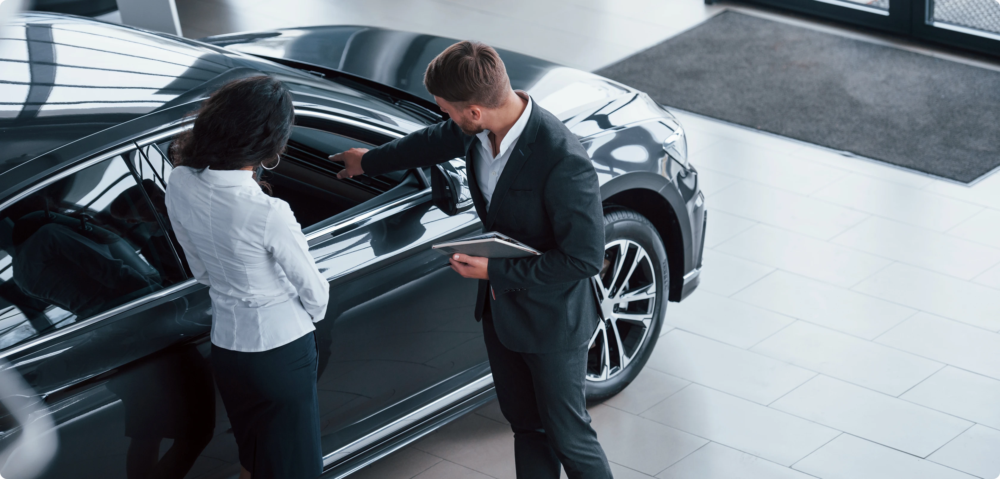 A dealership representative showing a buyer a vehicle